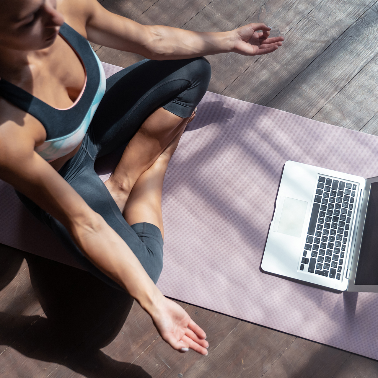 Frau in Yogaposition vor laptop